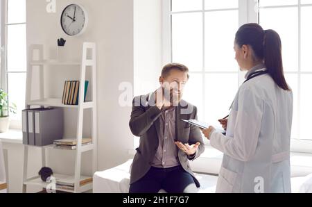 Patient mit akuter Fibromyalgie spricht mit dem Praktizierenden über seine Nackenschmerzen Stockfoto