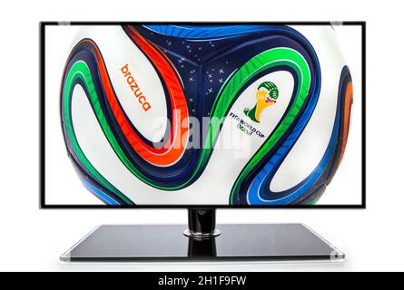 SWINDON, Großbritannien - 30. MAI 2014: Adidas Brazuca World Cup 2014 Football, der offizielle Matchball für die Weltmeisterschaft 2014 mit Fußballschuhen auf einem TV-Backgrou Stockfoto