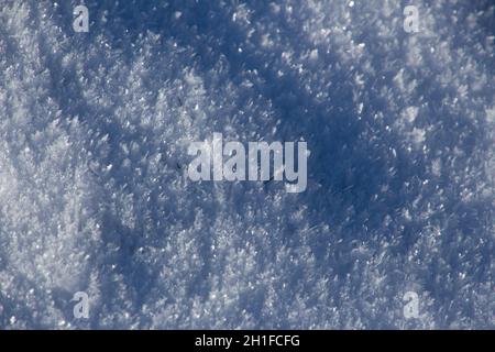 Frischer weißer Schnee funkelt in der Sonne mit Highlights und Schatten für den Hintergrund Stockfoto