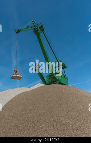 Grün grünen Greifkran füllt Sand von einem Hügel zum anderen Stockfoto