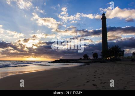 Fußabdrücke auf Sand, der zum Leuchtturm von Maspalomas bei herrlichem Sonnenuntergang am Strand der Kanarischen Inseln, Spanien, führt. Sommerurlaub, Reiseziel Stockfoto