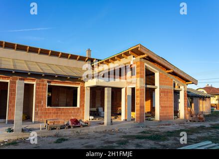 Haus unter Baubedingungen mit modernen Backsteinwänden und Löchern für Türen und Fenster Stockfoto