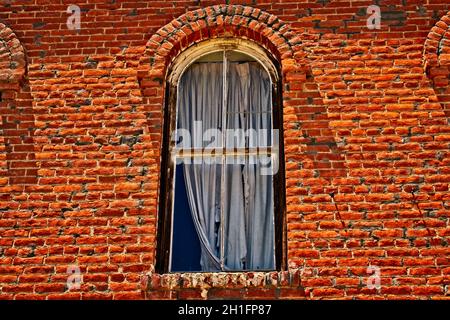 Vorhänge aus der Vergangenheit - Dies ist ein Fenster mit zerfetzten Vorhängen in einem der größeren Gebäude im Bodie State Historic Park Stockfoto