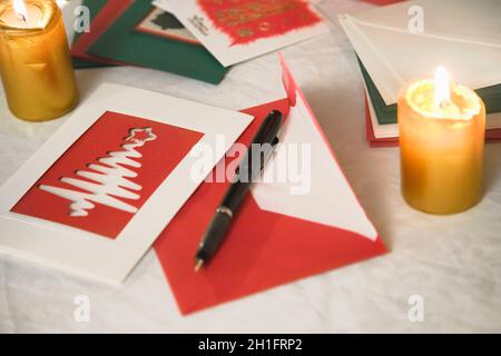 Auswahl von zu Hause gemacht Weihnachtskarten auf einem Tisch mit Umschlägen, Kerzen und einen Füllfederhalter Tinte Stockfoto