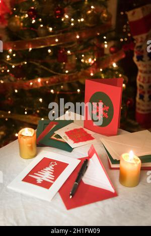 Auswahl von zu Hause gemacht Weihnachtskarten auf einem Tisch mit Umschlägen, Kerzen und einen Füllfederhalter Tinte Stockfoto