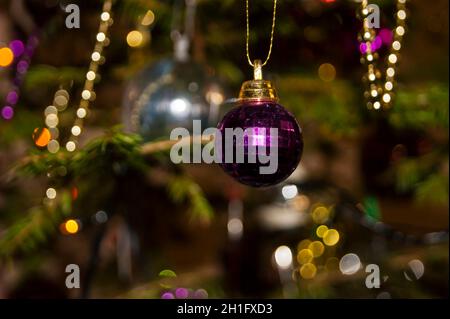 Silvester oder Weihnachten lebhaft elegant dekoriert FichtenNahaufnahme - Weihnachtsspielzeug vor dem Hintergrund von grünen Ästen und Lichtern. Stockfoto