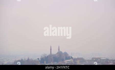 Nebliger Tag der Stadt Silhouette und gelbe Moschee auf einem kleinen Hügel in Bursa Türkei Stockfoto