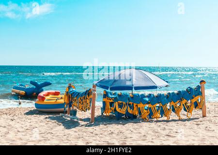 Gelbe Schwimmwesten am Strand sind bereit, im Meer oder Meer zu schwimmen. Sicheres Rafting und Bootszubehör. Rettungsweste retten Ihr Leben Stockfoto