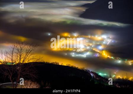 Lichter der Stadt unter dem dichten Nebel im Tal von Padana, Provinz Vicenza, Italien Stockfoto