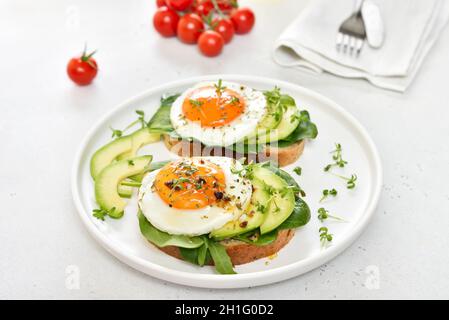 Spiegeleier, Avocado und Gemüse auf geröstetem Brot. Gesundes Frühstück Stockfoto