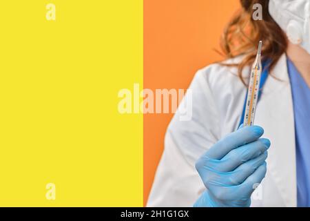 Eine Ärztin hält ein Quecksilberthermometer in der Hand. Medizinisches Instrument zur Messung der Körpertemperatur, Studio-Hintergrund Stockfoto