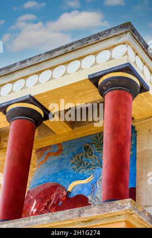 Der minoische Palast von Knossos mit seinen charakteristischen Säulen und einem Fresko eines Stiers dahinter. Kreta, Griechenland. Stockfoto