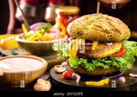 Vegane Quinoa-Burger mit Grünkohl, Salat, Tomaten, Pilzen und Tomatensauce auf rustikalem Hintergrund. Pflanzliches Lebensmittelkonzept Stockfoto