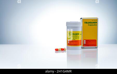 CHONBURI, THAILAND-MAY 24, 2020 : Transamin Kapseln mit Drogenflasche und Papierkarton mit Etikett Paket auf Gradienten Hintergrund. Orange-gelbe Kapsel p Stockfoto