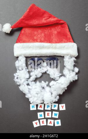 Samt Santa Hut mit Sonnenbrille Schnurrbart und Bart und Inschrift Frohes neues Jahr. Das Gesicht des Weihnachtsmanns. Urlaubspostkarte Stockfoto