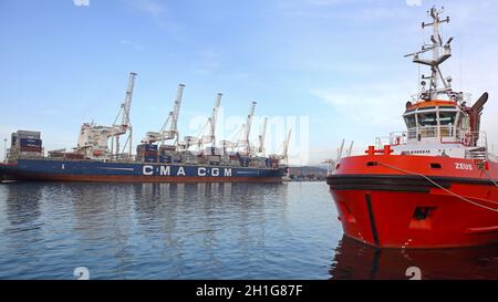 Koper, Slowenien - 14. Oktober 2014: Rotes Schlepper und langes Containerschiff im Hafen von Koper, Slowenien. Stockfoto