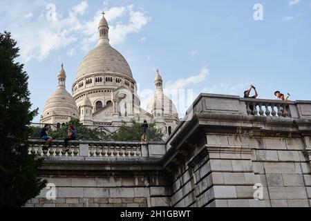 Paris, Frankreich - Juli 2019: Touristen, die Fotos machen und von dem Aussichtspunkt aus, der sich direkt die Treppe der Basilika Sacr befindet, aus über Paris blicken Stockfoto