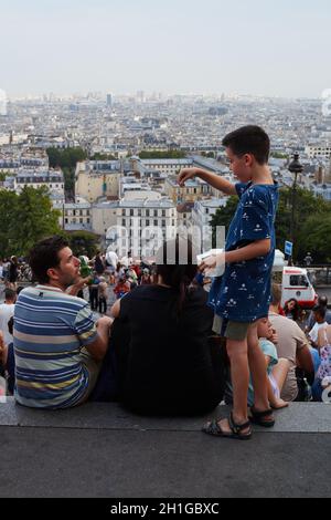 Paris, Frankreich - 2019. Juli: Familien von Touristen, die von der Treppe der Basilika des Heiligen Herzens (Basilique du Sacré-Cœur) in Mo über Paris blicken Stockfoto