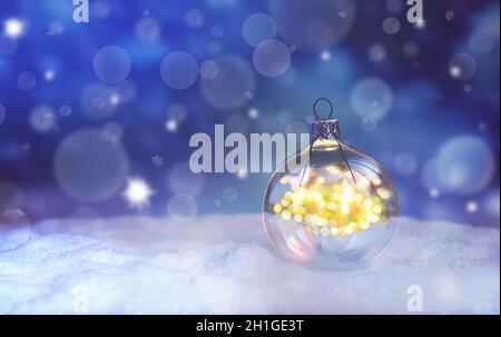 Schöne blaue Weihnachtskugel mit Lichtern auf Schnee und Winterhintergrund. Stockfoto