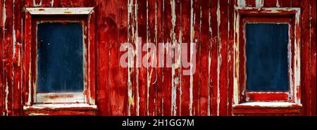 Abblätternde rote Farbe auf verwitterten alten Holzfensterrahmen auf Scheune oder Bauernhaus Stockfoto