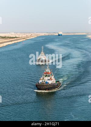 El Qantara, Ägypten - 14. November 2019: Schlepper begleiten die Schiffe. Schiffe, die durch den Suezkanal in Ägypten, Afrika, fahren. Stockfoto