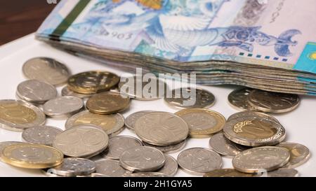 Eine Menge von Kasachstan Tenge auf einem weißen Teller.die Landeswährung von Kasachstan.Gehalt in Tenge.Count das Geld in Tenge.Lebensmittelkorb, Budget Einsparungen Stockfoto