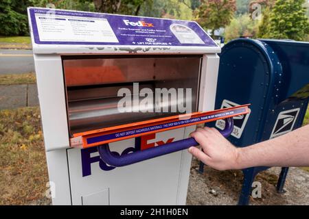 Kirkland, WA USA - ca. September 2021: Schräge Ansicht einer Hand, die eine FedEx-Paket- und Brieflagerstation-Tür in der Innenstadt von Kirkland aufzieht Stockfoto