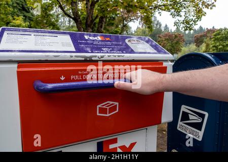 Kirkland, WA USA - ca. September 2021: Schräge Ansicht einer Hand, die eine FedEx-Paket- und Brieflagerstation-Tür in der Innenstadt von Kirkland aufzieht Stockfoto