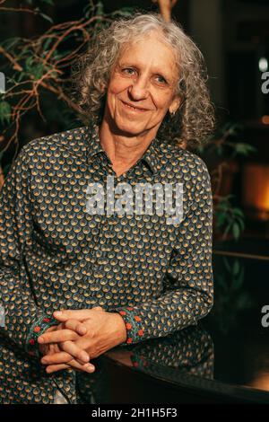 Porträt eines 65-jährigen Mannes mit grauen lockigen Haaren sieht weg, lächelt, Beruf Künstler, Musiker, Schauspieler. Menschlicher Körperteil Stockfoto