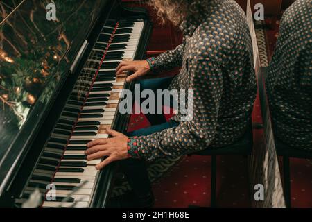 Menschliche Hände eines erwachsenen Mannes, der Melodie auf den Tasten des Klaviers oder des Flügels spielt. Nahaufnahme Lifestyle-Foto. Stockfoto