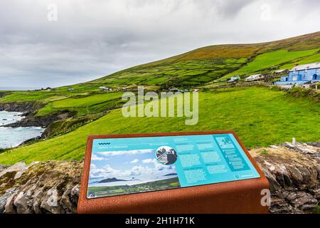 Dingle, Irland, Aug 2018 Informationstafel über den Aussichtspunkt Slea Head mit einem kleinen Häuschen am Ufer eines Berges im Hintergrund, Grafschaft Kerry Stockfoto