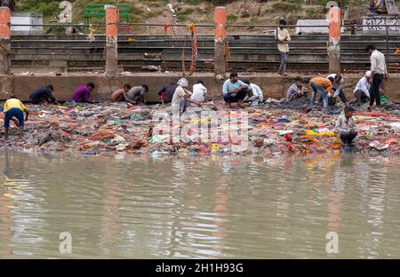 Muradnagar, Indien. Oktober 2021. Einheimische und ihre Kinder sieben Wertgegenstände aus den Stapeln am Ufer des Ganges-Kanals in Muradnagar.Einheimische Dorfbewohner suchen gerne nach wertvollen Gegenständen im Oberen Ganges-Kanal, der von schweren Bächen am Ufer des Kanals aufgetürmt wird. Eifrige Anhänger bieten während eines Tauchgangs im Ganga-Kanal Wertsachen als religiöse Praxis an oder verlieren sie dort unwissentlich. Kredit: SOPA Images Limited/Alamy Live Nachrichten Stockfoto