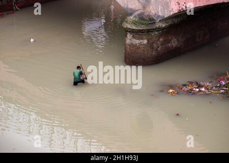 Muradnagar, Indien. Oktober 2021. Ein Einheimischer sucht mithilfe eines Spatens im Ganges-Kanal bei Muradnagar nach wertvollen Gegenständen.im oberen Ganges-Kanal, der von starken Bächen am Ufer des Kanals aufgetürmt wird, suchen Einheimische gerne nach wertvollen Gegenständen. Eifrige Anhänger bieten während eines Tauchgangs im Ganga-Kanal Wertsachen als religiöse Praxis an oder verlieren sie dort unwissentlich. Kredit: SOPA Images Limited/Alamy Live Nachrichten Stockfoto