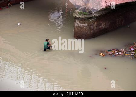 Muradnagar, Indien. Oktober 2021. Ein Einheimischer sucht mithilfe eines Spatens im Ganges-Kanal bei Muradnagar nach wertvollen Gegenständen.im oberen Ganges-Kanal, der von starken Bächen am Ufer des Kanals aufgetürmt wird, suchen Einheimische gerne nach wertvollen Gegenständen. Eifrige Anhänger bieten während eines Tauchgangs im Ganga-Kanal Wertsachen als religiöse Praxis an oder verlieren sie dort unwissentlich. (Foto von Pradeep Gaur/SOPA Images/Sipa USA) Quelle: SIPA USA/Alamy Live News Stockfoto