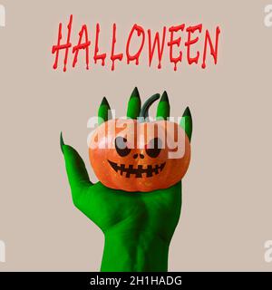 Zombie's grüne Hand mit Kürbis. Halloween Minimalkonzept. Stockfoto