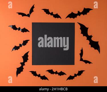 Kreativer Halloween Hintergrund aus Fledermäusen und schwarzer Papierkarte. Minimales Urlaubskonzept. Flach liegend. Stockfoto