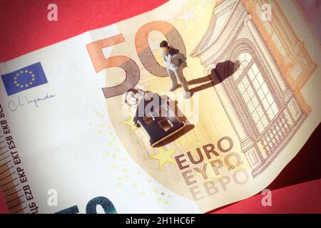 Miniatur-Geschäftsmann in einer 50-Euro-Banknote und einem Häusersymbol. Stockfoto