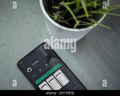LOD, Israel - 8. Juli 2020: Moderner minimalistischer Büroarbeitsplatz mit schwarzem Smartphone mit GitHub App Play Store Seite auf Marmor Hintergrund. Oben Stockfoto