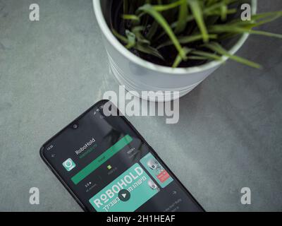 LOD, Israel - 8. Juli 2020: Moderner minimalistischer Büroarbeitsplatz mit schwarzem Smartphone mit RoboHOLD App Play Store Seite auf Marmorhintergrund. Bis Stockfoto