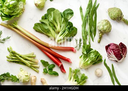 Flat Lay mit veganen Zutaten: Salat und Gemüse Draufsicht auf weißem Marmortisch als Muster angeordnet Stockfoto