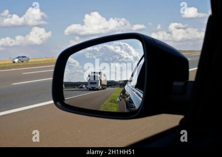 LKW auf einer Autobahn gesehen im Rückspiegel an einem Sommertag. Stockfoto