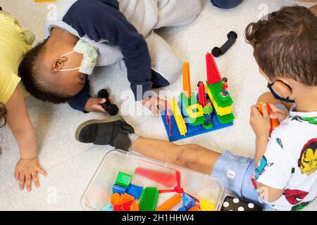 Bildung Vorschule 3-4-jährige zwei Jungen spielen zusammen Gebäude mit verbindenden bunten Plastikblöcken Stockfoto
