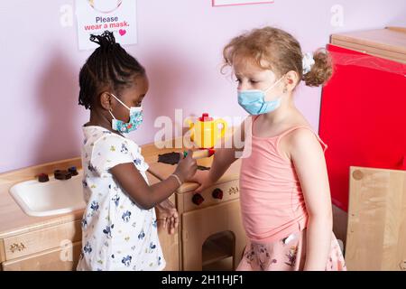 Bildung Vorschule 4-5-Jährige zwei Mädchen spielen im Familienbereich, eines gibt dem anderen eine Chance in der are Stockfoto