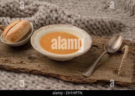 Schüssel mit Kürbissuppe und Laib Brot im Winter auf dem Bett Stockfoto