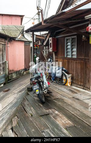 George Town, Penang, Malaysia - 1. Dezember 2019: Motorrad und Fahrräder auf dem hölzernen Bürgersteig des berühmten Fischerdorfes Clan Tan Jetty in Geo Stockfoto