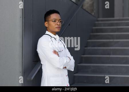 Müde Ärztin nach einem harten Tag in der Klinik, eine afroamerikanische Frau in der Klinik mit starken Kopfschmerzen und Depressionen nach Überlastung Stockfoto