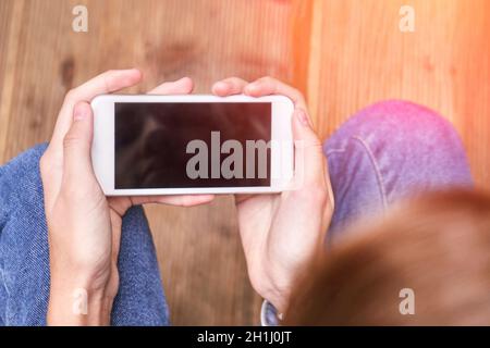 Hübsches Mädchen im Freien. Echte Menschen, die ein Mobiltelefon nutzen. Alleinerziehende weibliche Person Stockfoto