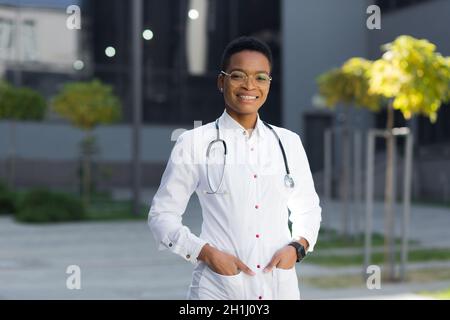 Porträt der weiblichen Kinderarzt Arzt glücklich erfolgreich lächelnd und Blick auf Kamera in der Nähe der Klinik im medizinischen Kleid Stockfoto