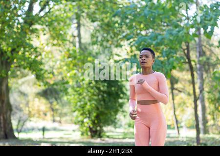 Junge schöne afroamerikanische Frau beim Joggen am Morgen im Herbstpark Stockfoto