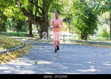 Junge schöne afroamerikanische Frau beim Joggen am Morgen im Herbstpark Stockfoto